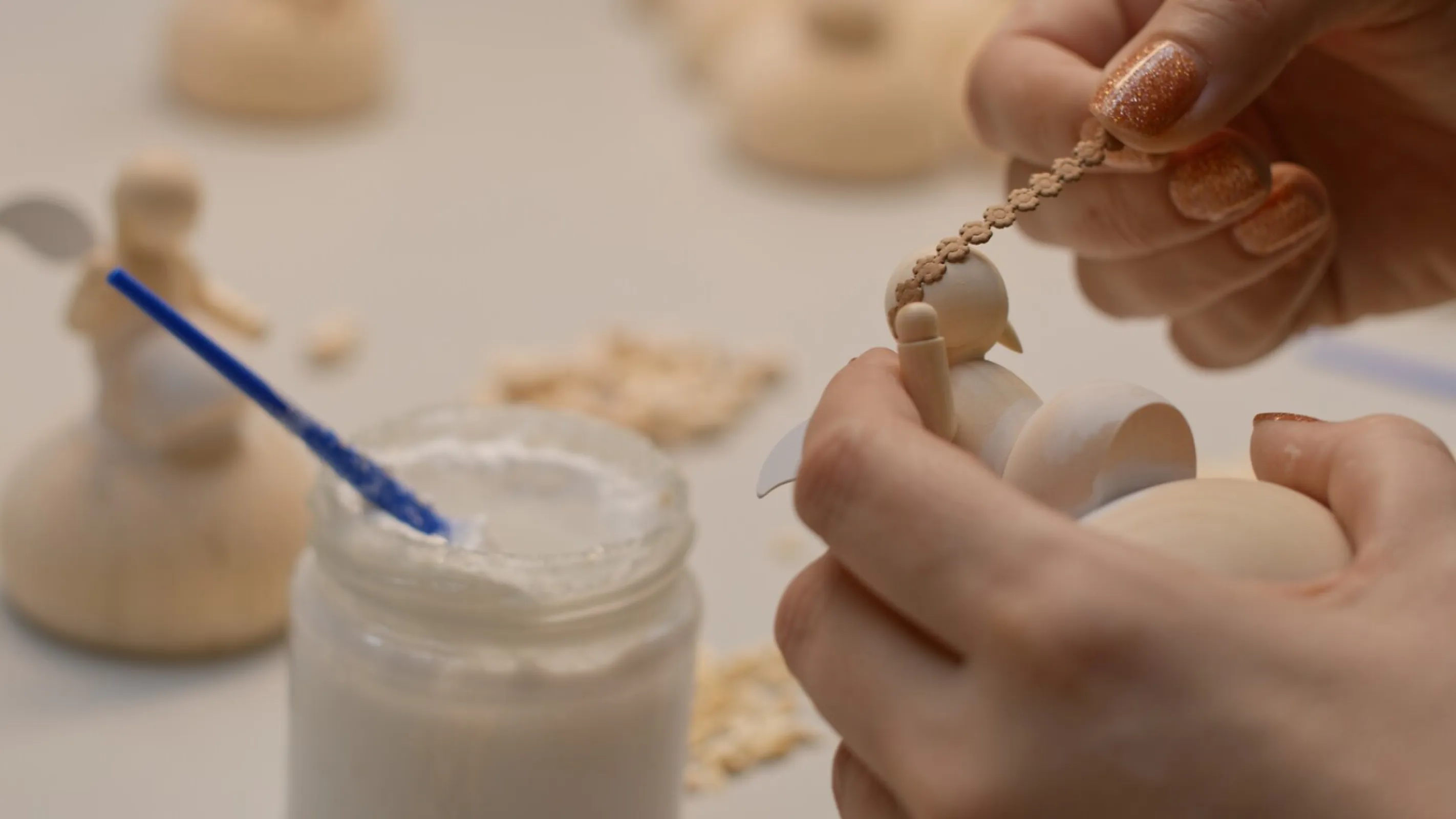 In the gluing workshop, a daisy wreath is glued to a small angel's head.