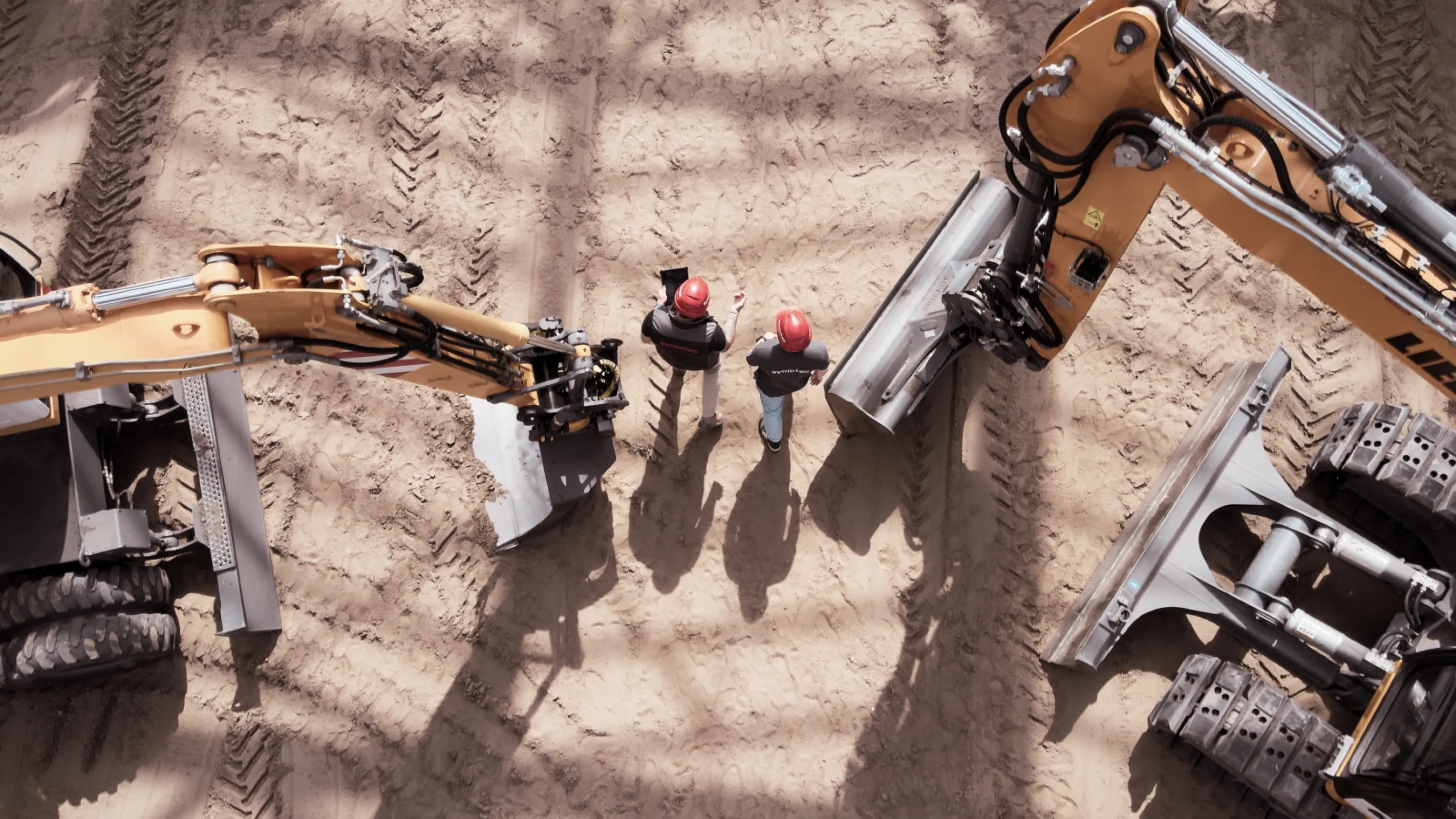 Top-down view of two excavators and operators on a construction site – showcasing real use cases of syniotec tracking.