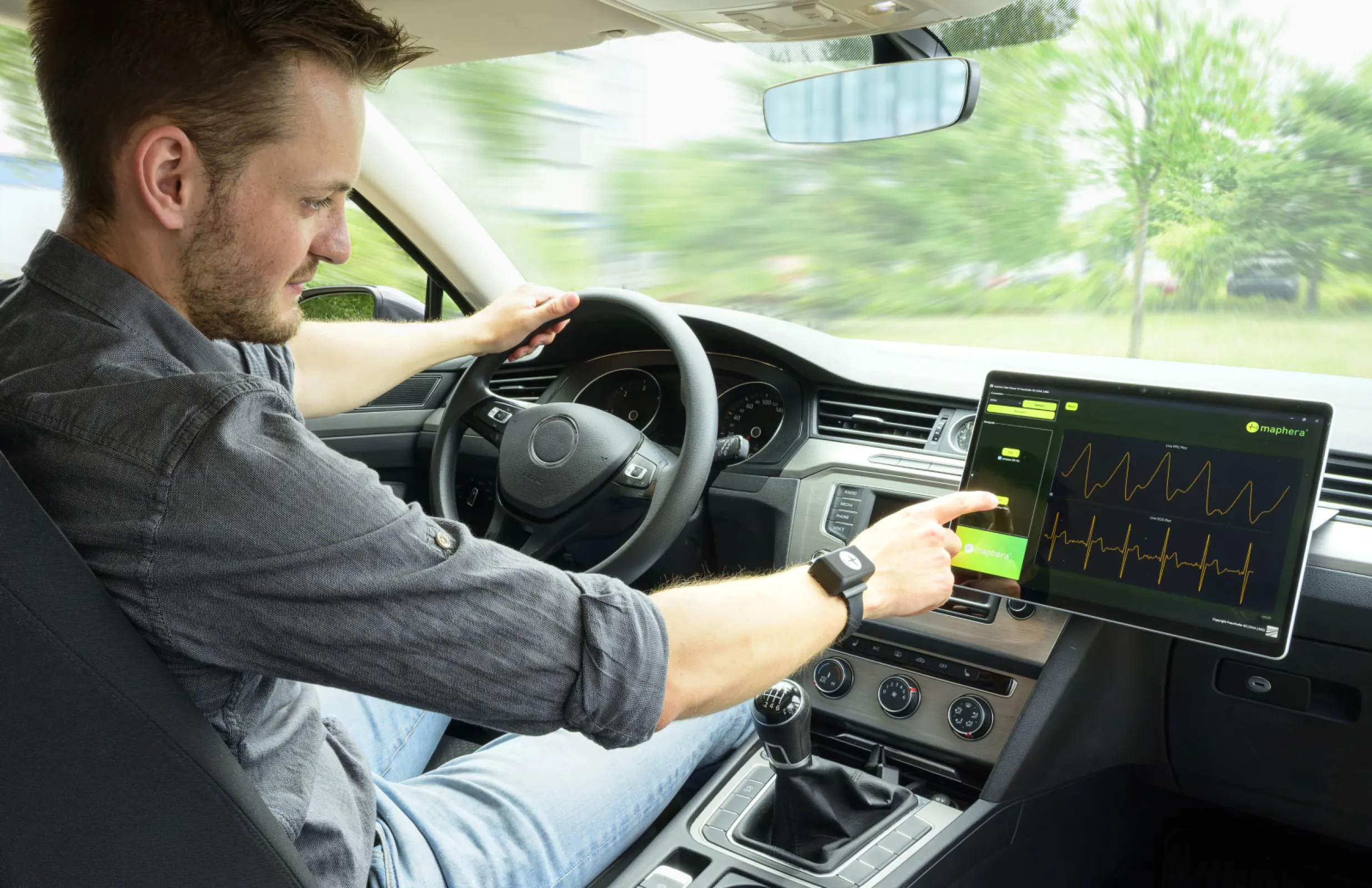 Unobtrusive while driving: Driver using maphera® wrist sensor node and chest strap with user interface displayed on tablet (©Fraunhofer IIS/Paul Pulkert)
