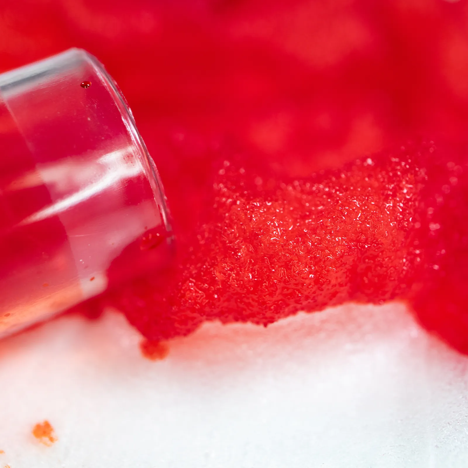 Macro close-up showing DEBAMED® Speci-Sorb absorbing red liquid from a sample tube, highlighting the porous surface saturated with fluid.