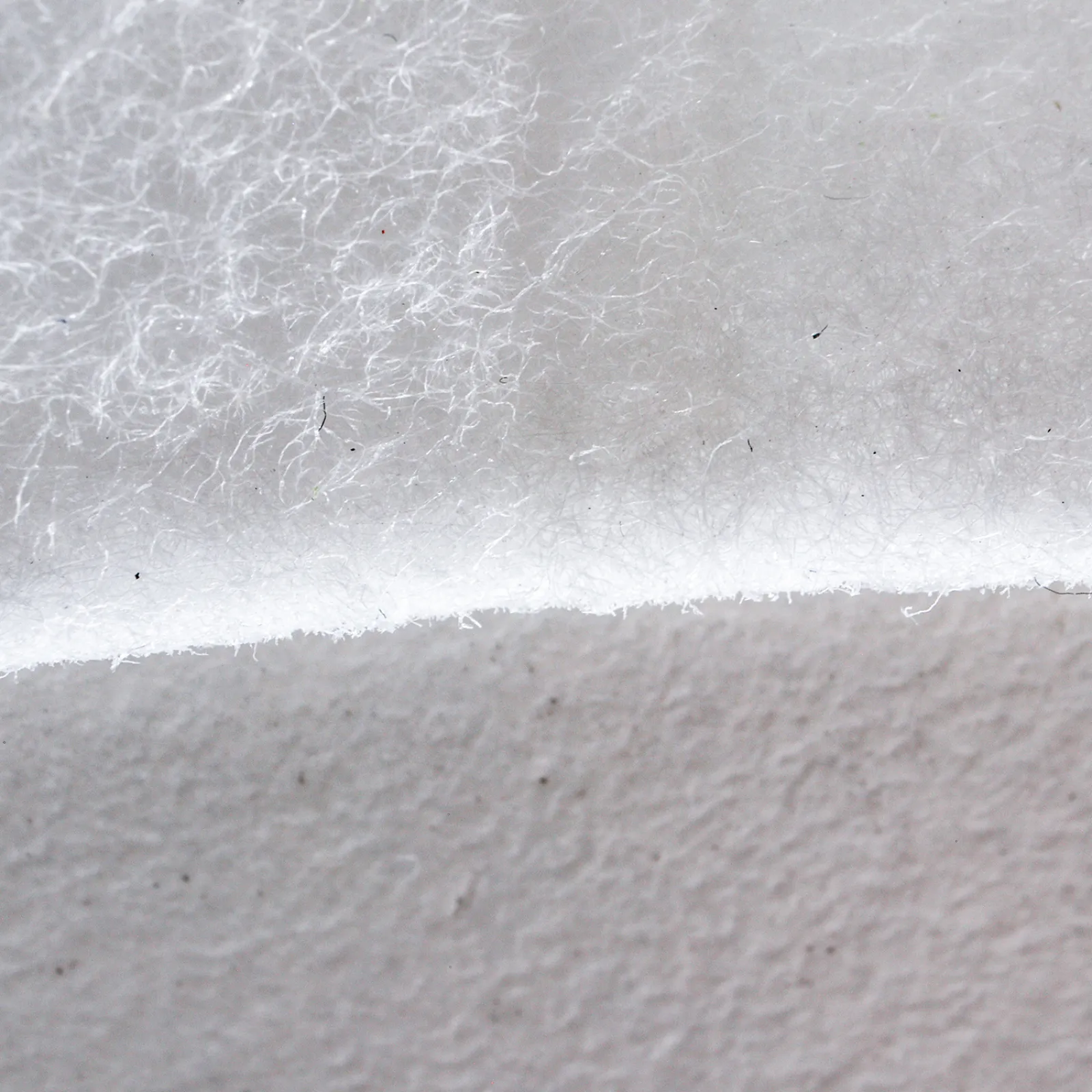 Macro close-up of the DEBAMED® Absorber with Compartments material, showing a soft, fibrous white texture.