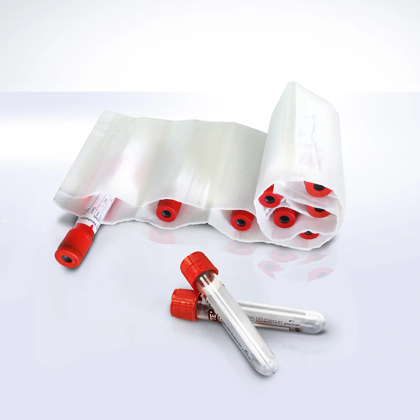 DEBAMED® Absorber with Compartments rolled up, holding multiple red-topped sample tubes; two additional tubes lie in front on a glossy white surface.