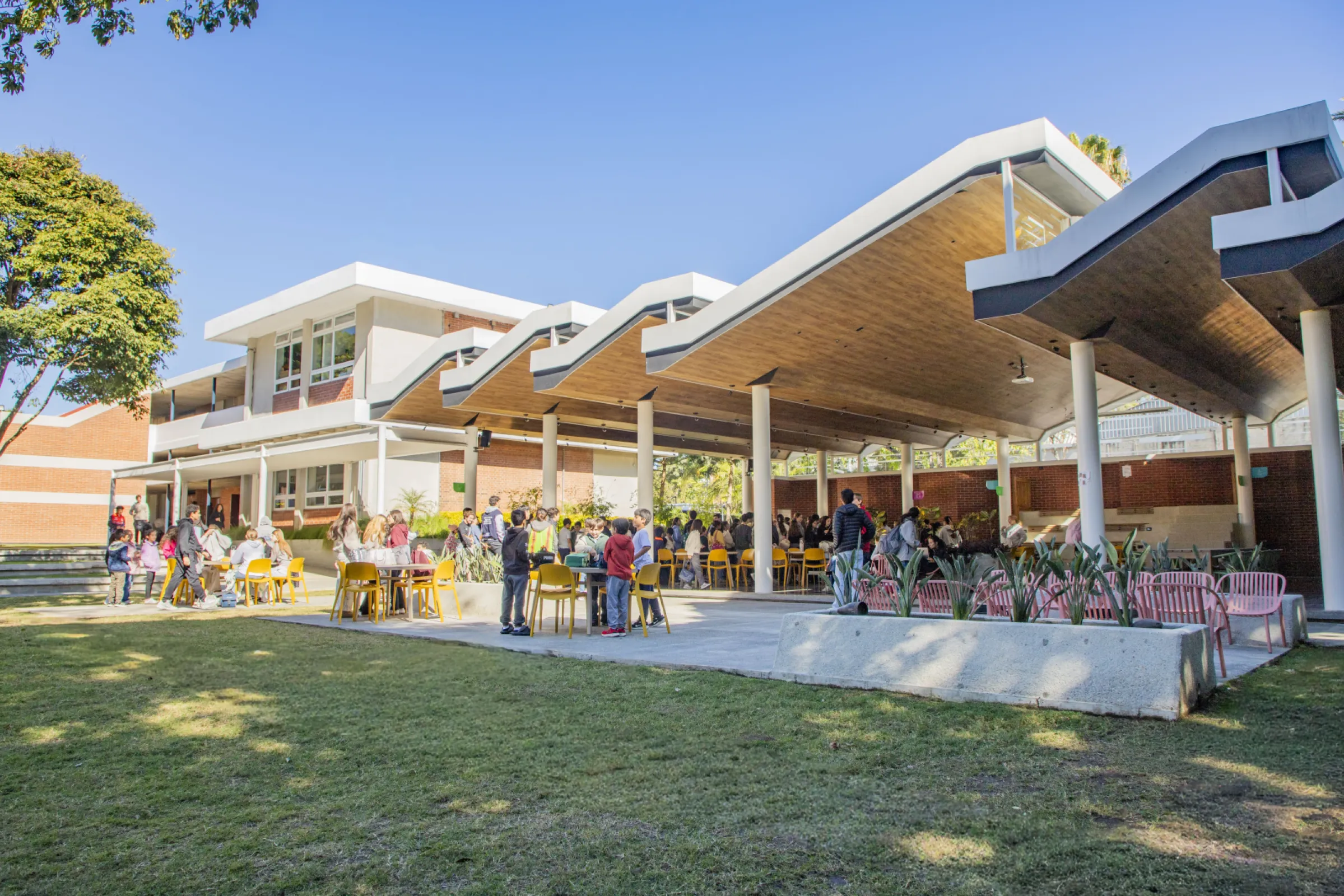 The open-plan cafeteria is a lively meeting place where students of different age groups and teachers come together to eat, connect, and work on projects.