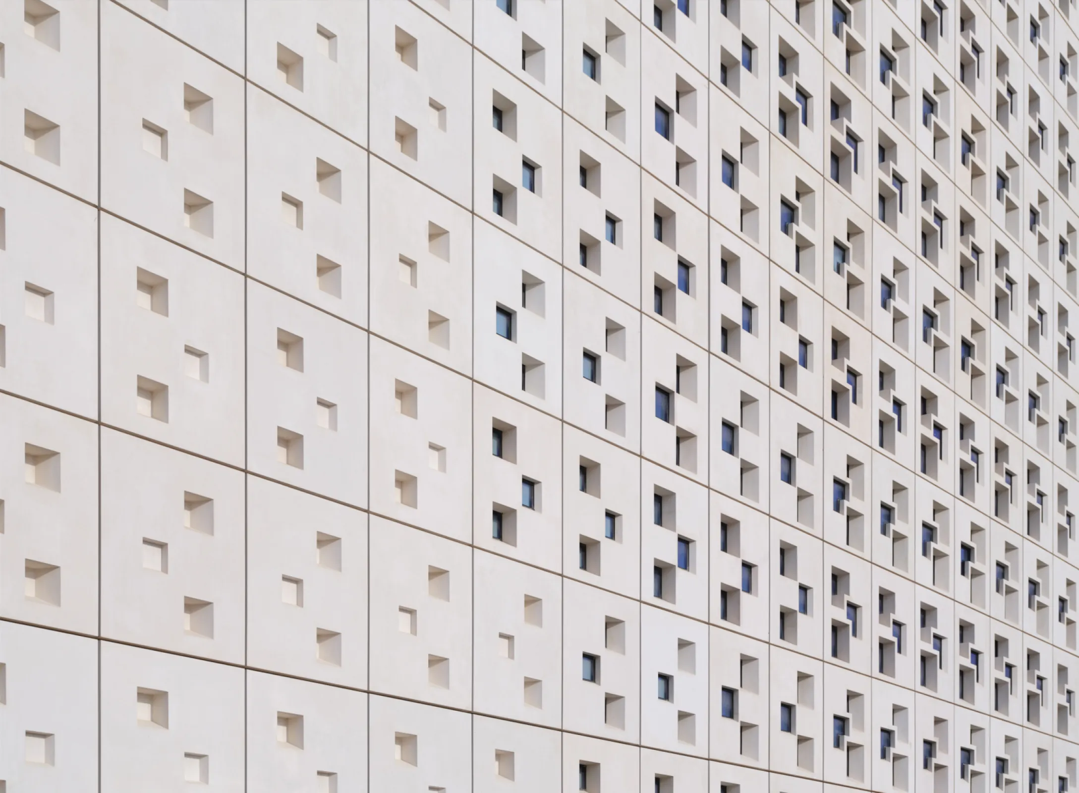 Windows and fibre-reinforced concrete elements form a patterned façade that filters sunlight. Its geometry echoes the stacked meeting voxels within, translating the tower’s spatial concept into a climate-responsive architectural skin. Photo: Taufik Kenan